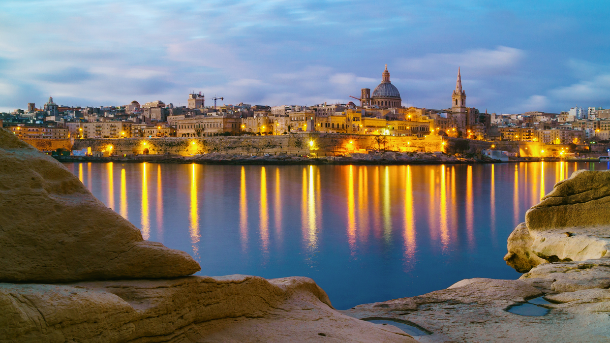 The Valletta skyline and cathedral dome across the water at dusk